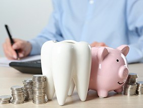 Piggy bank next to coins and a tooth