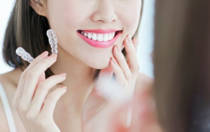 Woman looking at smile and holding an Invisalign tray