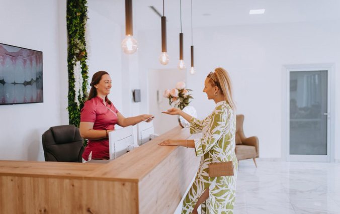 Lady converses with receptionist at dentist’s office